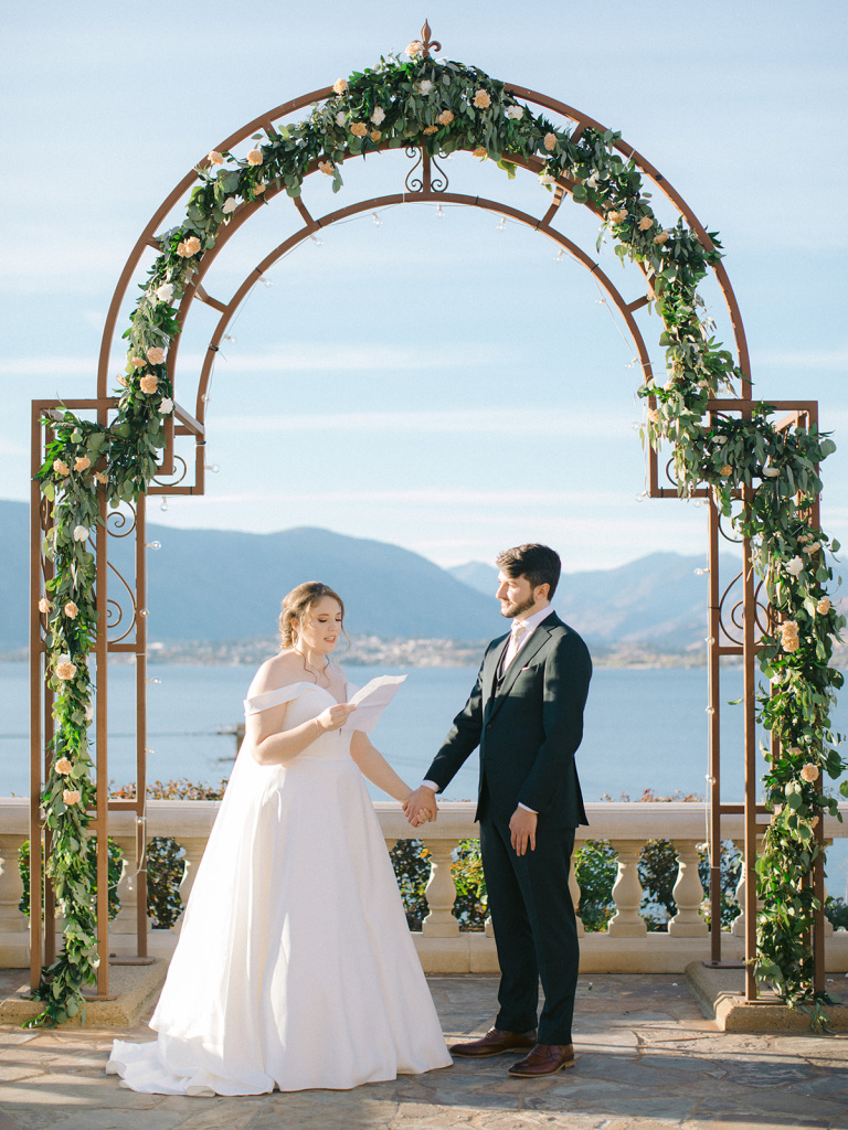 Bride sharing vows while holding hands with groom at Lake Chelan