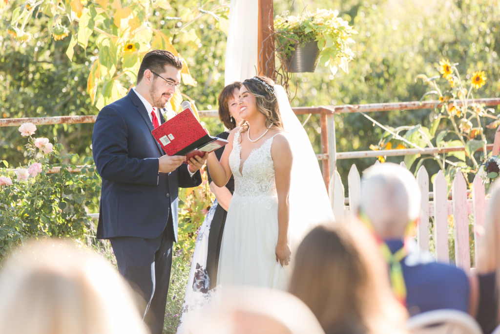 Groom reading vows from red journal to laughing bride at Wenatchee